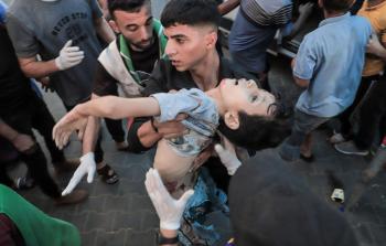 فلسطيني يحمل جثمان طفل فلسطيني وسط غزة