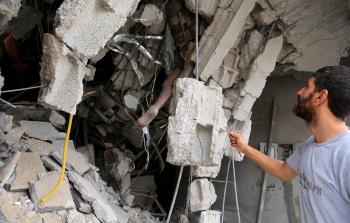 شاب ينظر لجثة فلسطيني بين ثنايا ركام المنزل الذي قصف على من فيه (تصوير: الأناضول)