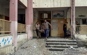 مواطنون ينتشلون إحدى ضحايا جرائم الاحتلال من مدرسة للنازحين تم استهدافها بغارة جوية