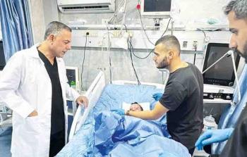 الدكتور حسام أبو صفية إلى جانب أحد المرضى في مستشفى كمال عدوان