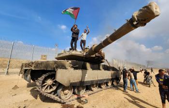 مشهد من يوم 7 من أكتوبر 2023 فيه يعتلي مواطنون دبابة إسائيلية