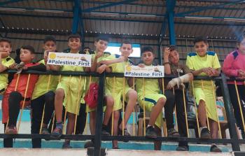 أطفال يلعبون كرة القدم يرفعون لافتات كتب عليها 