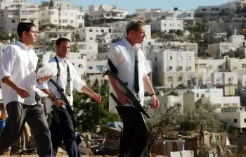 مستوطنون يتجولون بأسلحتهم قرب مدينة الخليل بالضفة الغربية