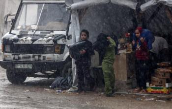 أطفال يحاولون حماية أنفسهم من الأمطار الغزيرة بغزة