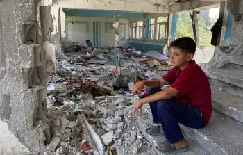 طفل يجلس وسط أنقاض مدرسة دمرها الاحتلال في النصيرات وسط قطاع غزة