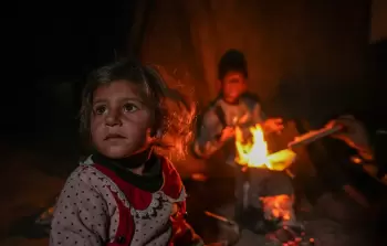 أطفال يتجمعون حول النار وسط البرد القارس في خيام النازحين بخانيونس وسط قطاع غزة