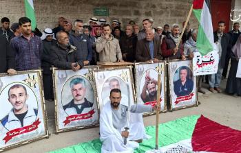 أحد أهالي الأسرى يرتدي كفنًا تجسيدًا للموت البطيء الذي يعيشه الأسرى في سجون الاحتلال