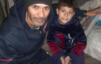 التاجر عامر مرتجى برفقة ابنه داخل خيمة النزوح في يوم شتوي بارد