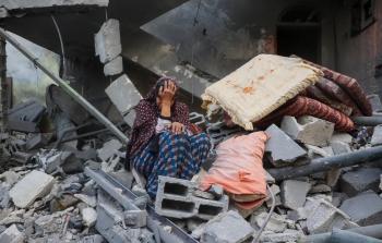 سيدة تجلس على ركام منزلها الذي قصفه الاحتلال خلال حرب الإبادة الجماعية (الفرنسية)