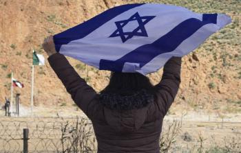 امرأة على الجانب المغربي من الحدود، وهي ترفع علم الاحتلال الإسرائيلي