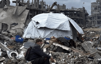 رجل يجلس قرب خيمته فوق دمار منزله الذي قصفه الاحتلال خلال الإبادة الجماعية بغزة