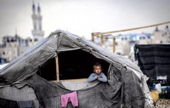 طفل يجلس داخل خيمة مهترئة يحاول البحث عن الدفء