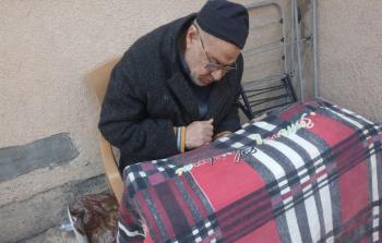 يجلس أبو تامر علي متكئًا على “الووكر” يراقب خطواته القليلة كما لو كانت إنجازًا يوميًا شاقًا