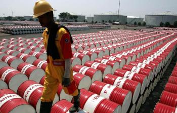 عامل يسير فوق براميل تُستخدم عادةً لتخزين ونقل المنتجات النفطية والمشتقات الهيدروكربونية (أرشيف)