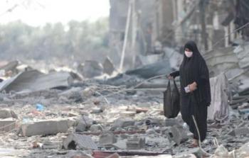 سيدة من غزة تقف بين الدمار الذي خلفه قصف الاحتلال خلال حرب الإبادة الجماعية