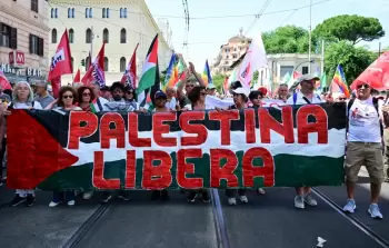 متظاهرون في مدينة روما الإيطالية يحملون لافتة كُتب عليها 