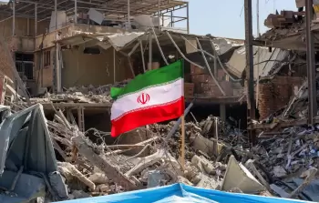 العلم الإيراني يرفرف فوق مبنى دمره العدوان الإسرائيلي الأمريكي