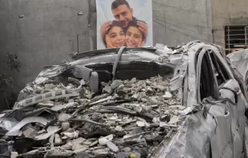 صورة أب وطفليه معلقة على جدار منزلهم الذي استهدفته الغارات الإسرائيلية وقتلتهم جميعا في قرية ساكساكية جنوب لبنان (أسوشيتد برس)