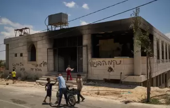 أطفال يقفون خارج مسجد أُحرق خلال هجوم شنه مستوطنون إسرائيليون في قرية قصرة بالضفة الغربية الأحد الماضي