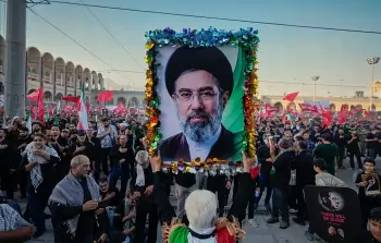 رجل يحمل صورة المرشد الأعلى الإيراني الجديد مجتبى خامنئي