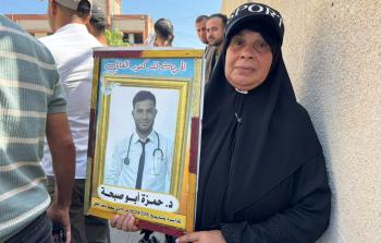 والدة الدكتور حمزة أبو صبحة تحمل صورته خلال وقفة بغزة