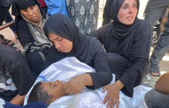 والدة الشهيد الطفل معتز أبو شعر (8 أعوام) خلال إلقاء نظرة الوداع عليه أمس (تصوير| رمضان الآغا)