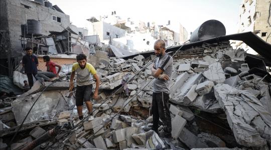 مواطنون يقفون فوق أنقاض منزل دمَّره الاحتلال بغزة (أرشيفية)