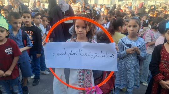 طالبة ترفع لافتة كتب عليها "هنا نلتقى، هنا نتعلم لنبني"